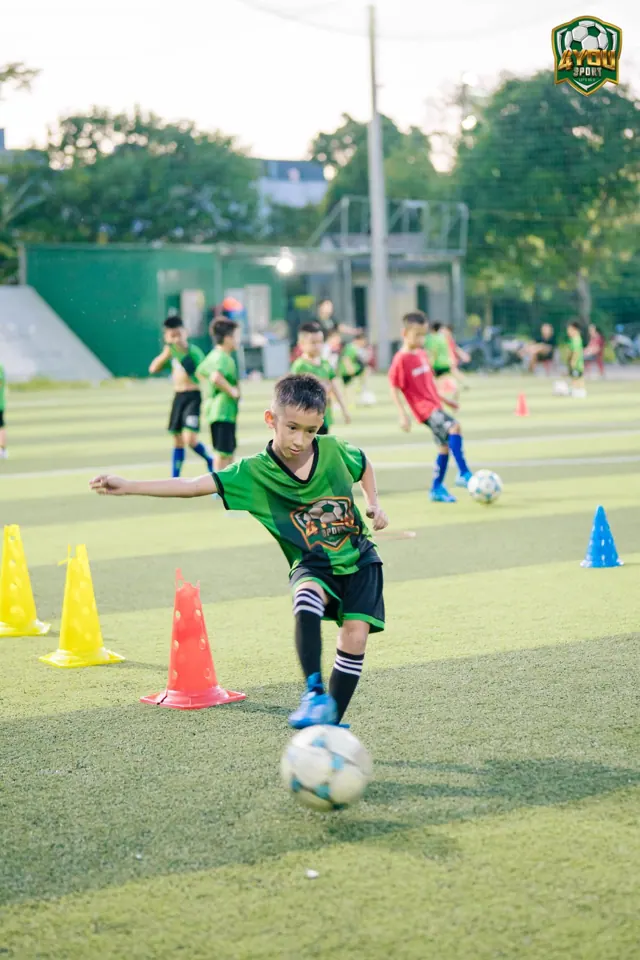 Bé dẫn bóng qua cọc trong buổi tập