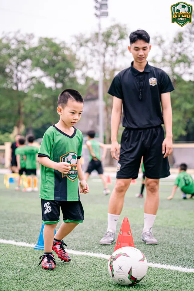 HLV kèm một bé dẫn bóng qua cọc